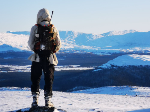 Mann på jakt på fjellet i snølandskap